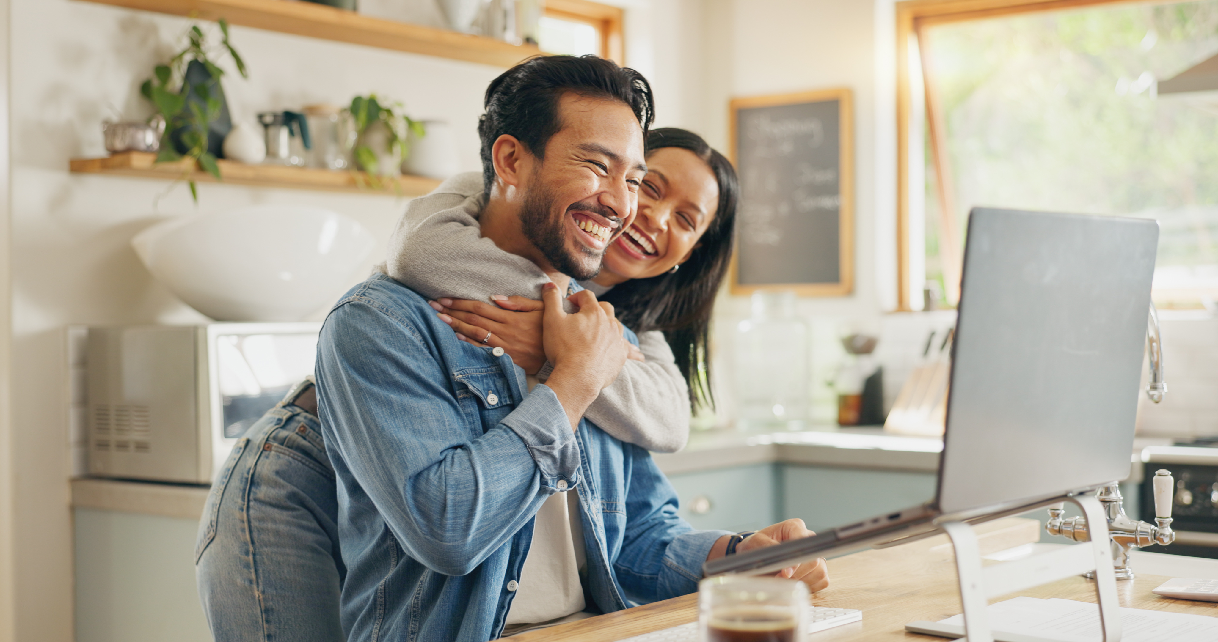Happy couple laughing and embracing in a modern home kitchen